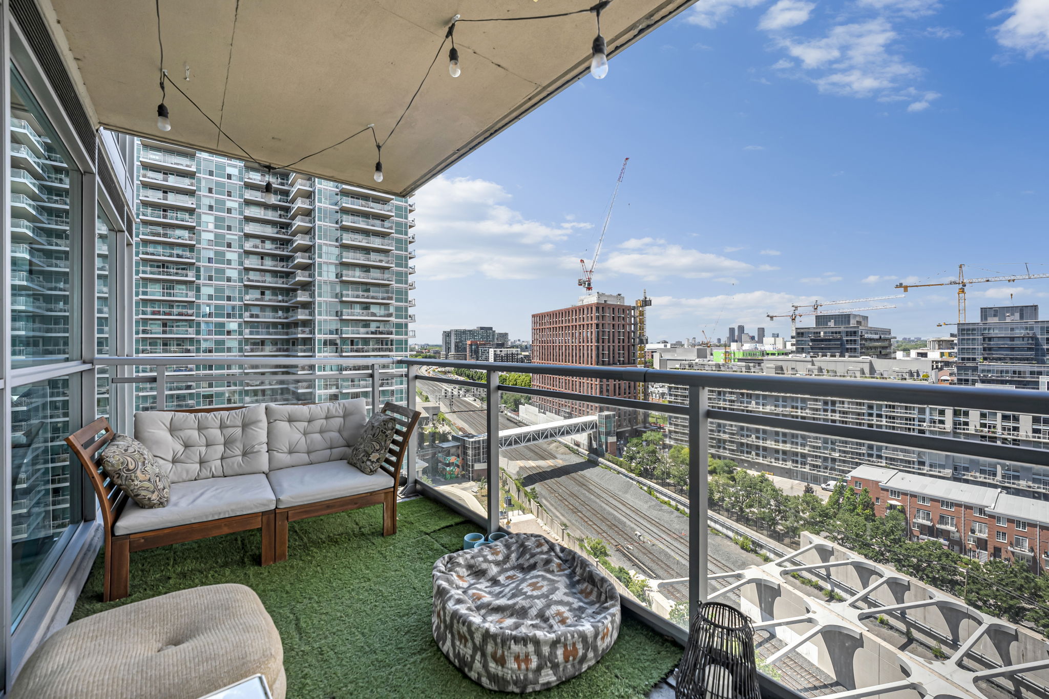 Furnished balcony with string lights, outdoor sofa and Liberty Village skyline views at 80 Western Battery Rd, Toronto