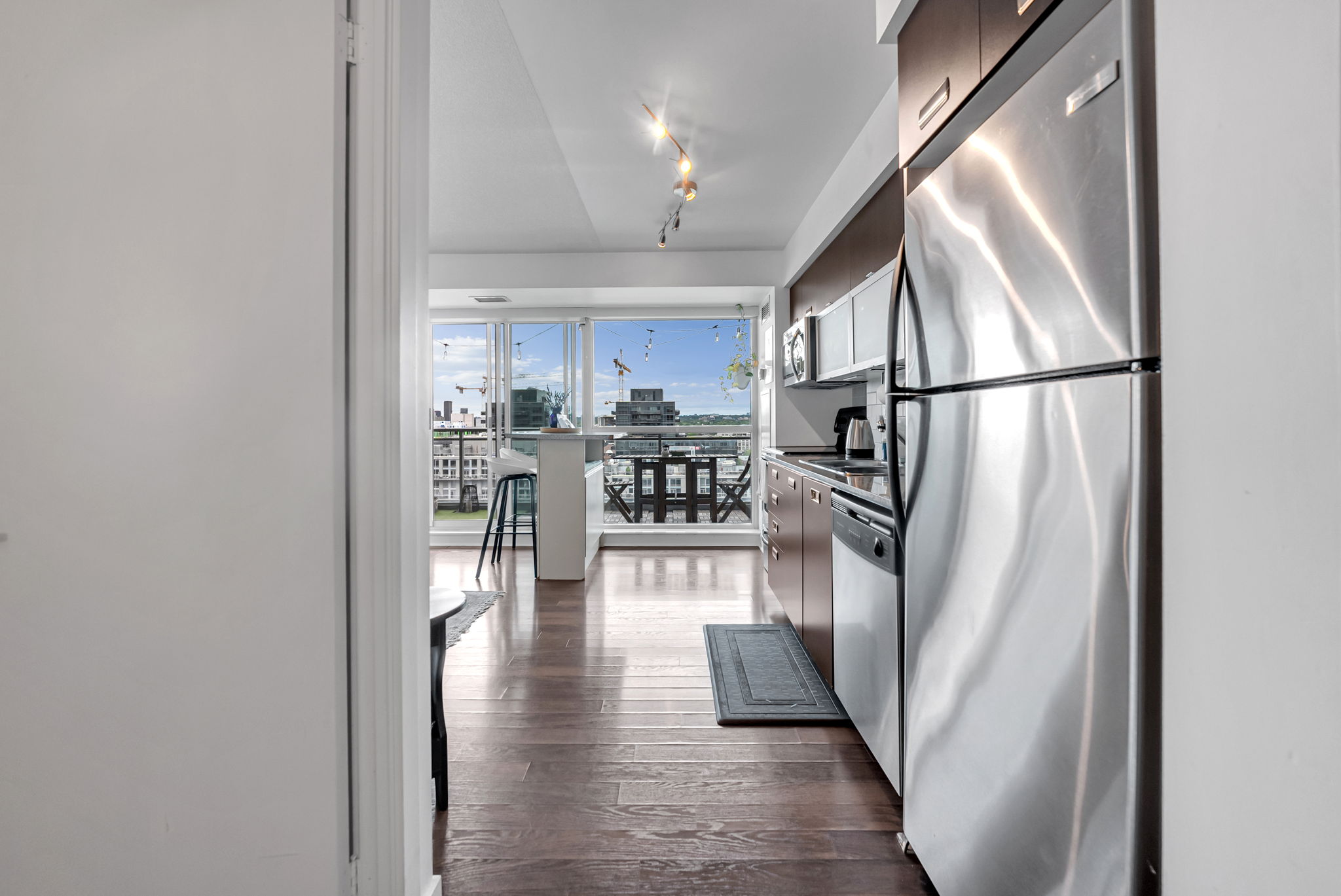 Kitchen with stainless appliances opening to a bright living area and balcony in a Certus-managed rental at 80 Western Battery Rd, Liberty Village