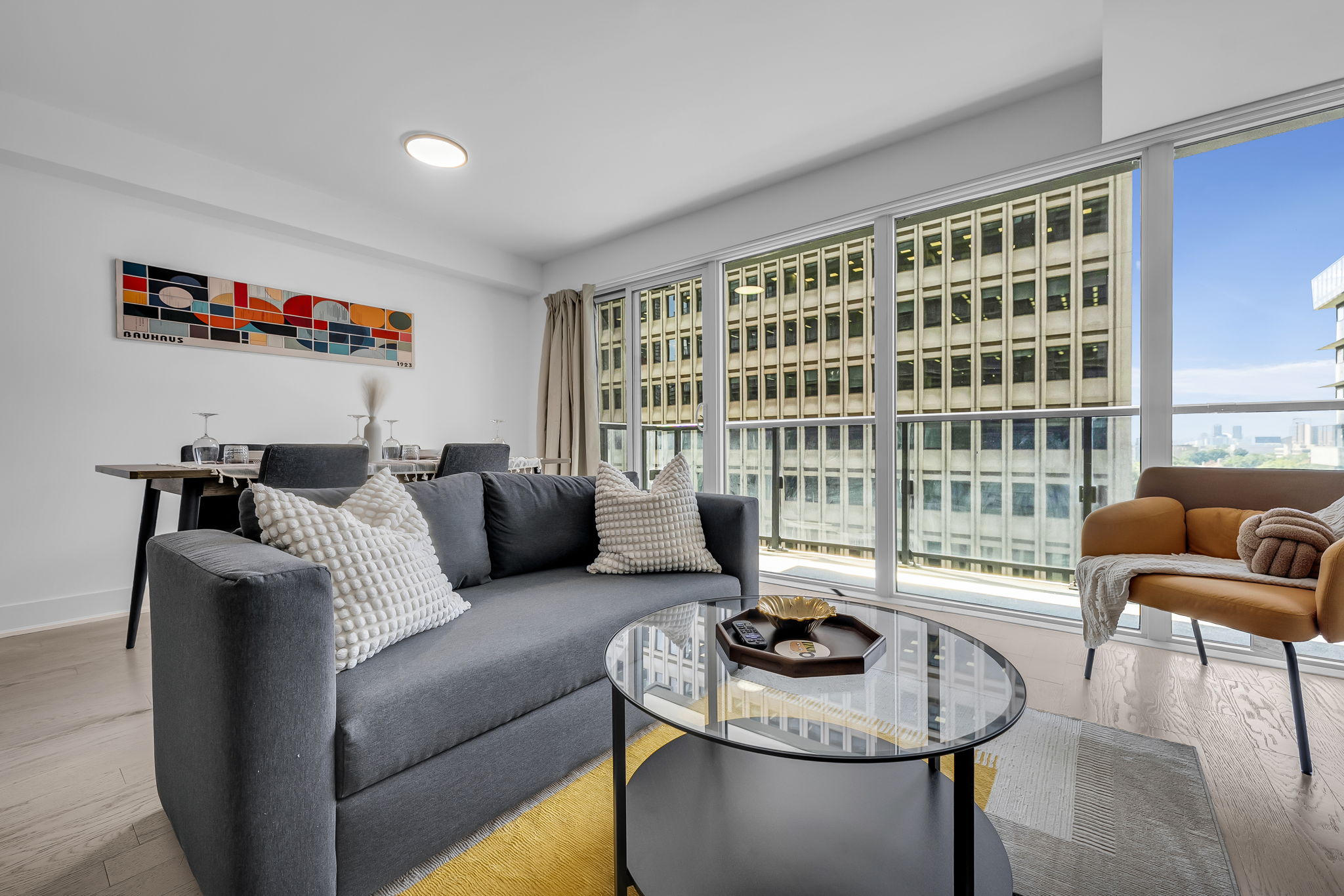 Furnished living room with grey sofa and floor-to-ceiling windows at 955 Bay St, Toronto